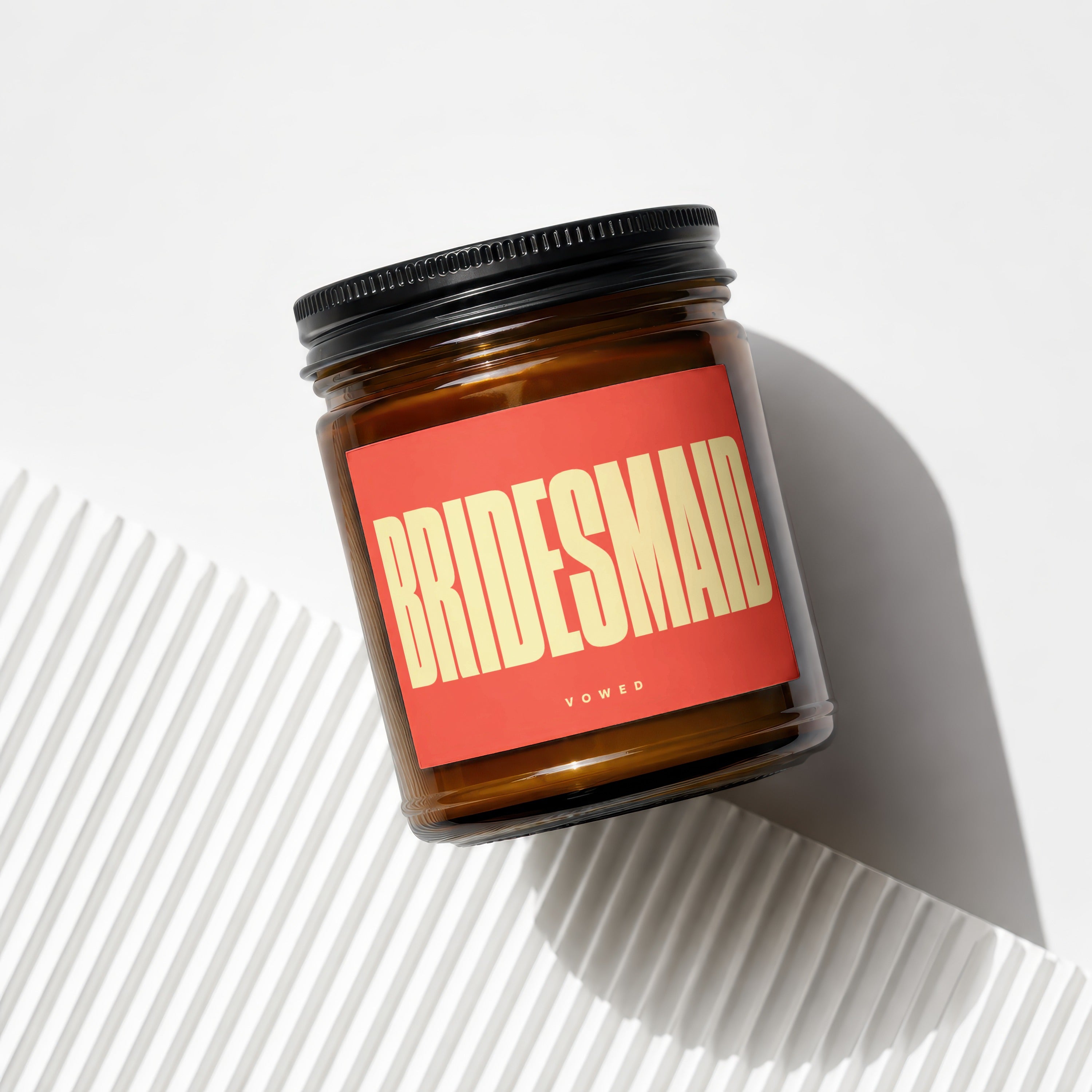 Amber jar candle with red label reading "BRIDESMAID" and "vowed".
