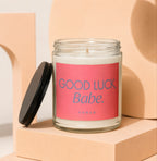 Glass candle with pink label reading "Good Luck, Babe. Vowed."