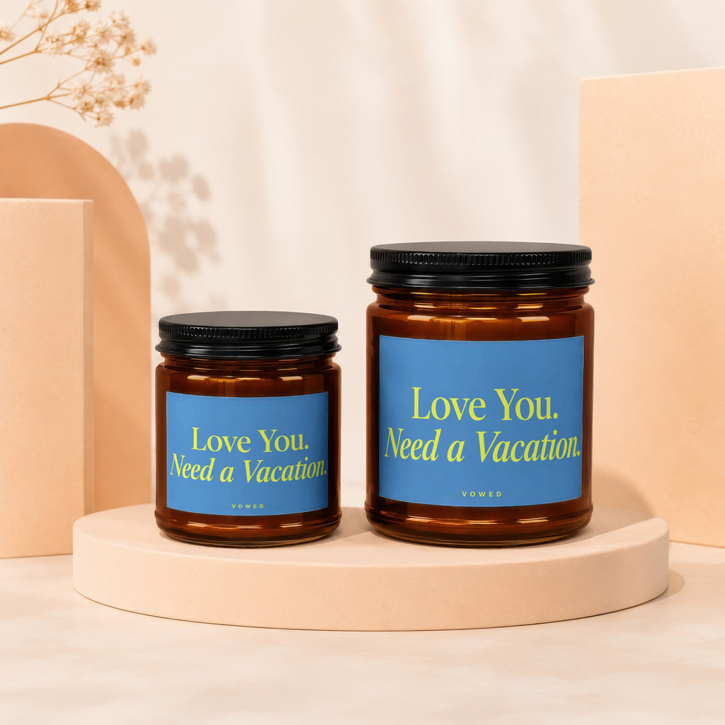Two amber glass candles with blue labels saying "Love You. Need a Vacation."