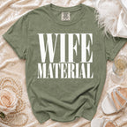 Olive green t-shirt with "WIFE MATERIAL" printed in white block letters.