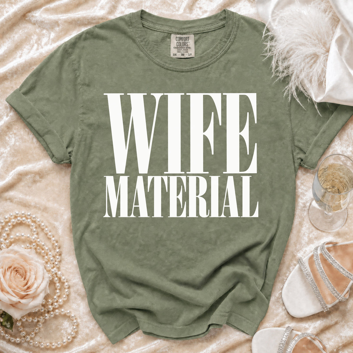 Olive green t-shirt with "WIFE MATERIAL" printed in white block letters.