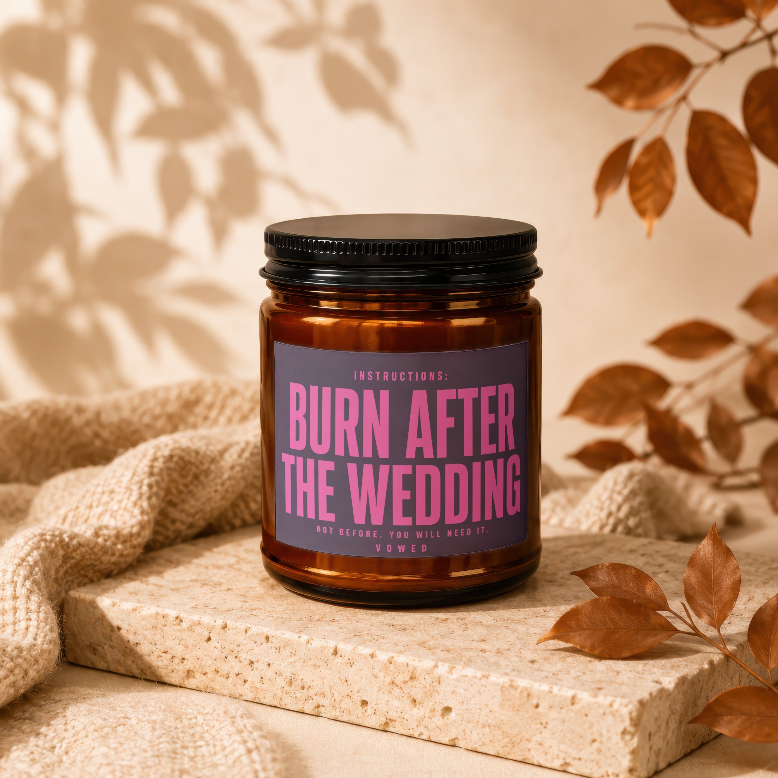 Amber candle with black lid, pink text reads "Burn After The Wedding".