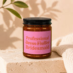 Candle with pink label reading "Professional Dress Fluffer" and "Bridesmaid" by VOWED.
