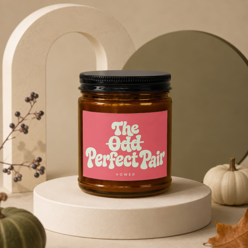 Amber candle with black lid and pink label reading "The Odd Perfect Pair".