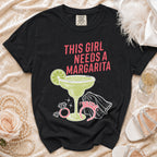 Black t-shirt with "This Girl Needs a Margarita" text and margarita graphic.