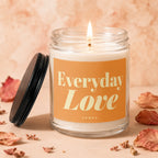 Candle with lit wick, orange label that reads "Everyday Love Vowed".