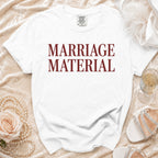 White t-shirt with "MARRIAGE MATERIAL" printed in maroon text.