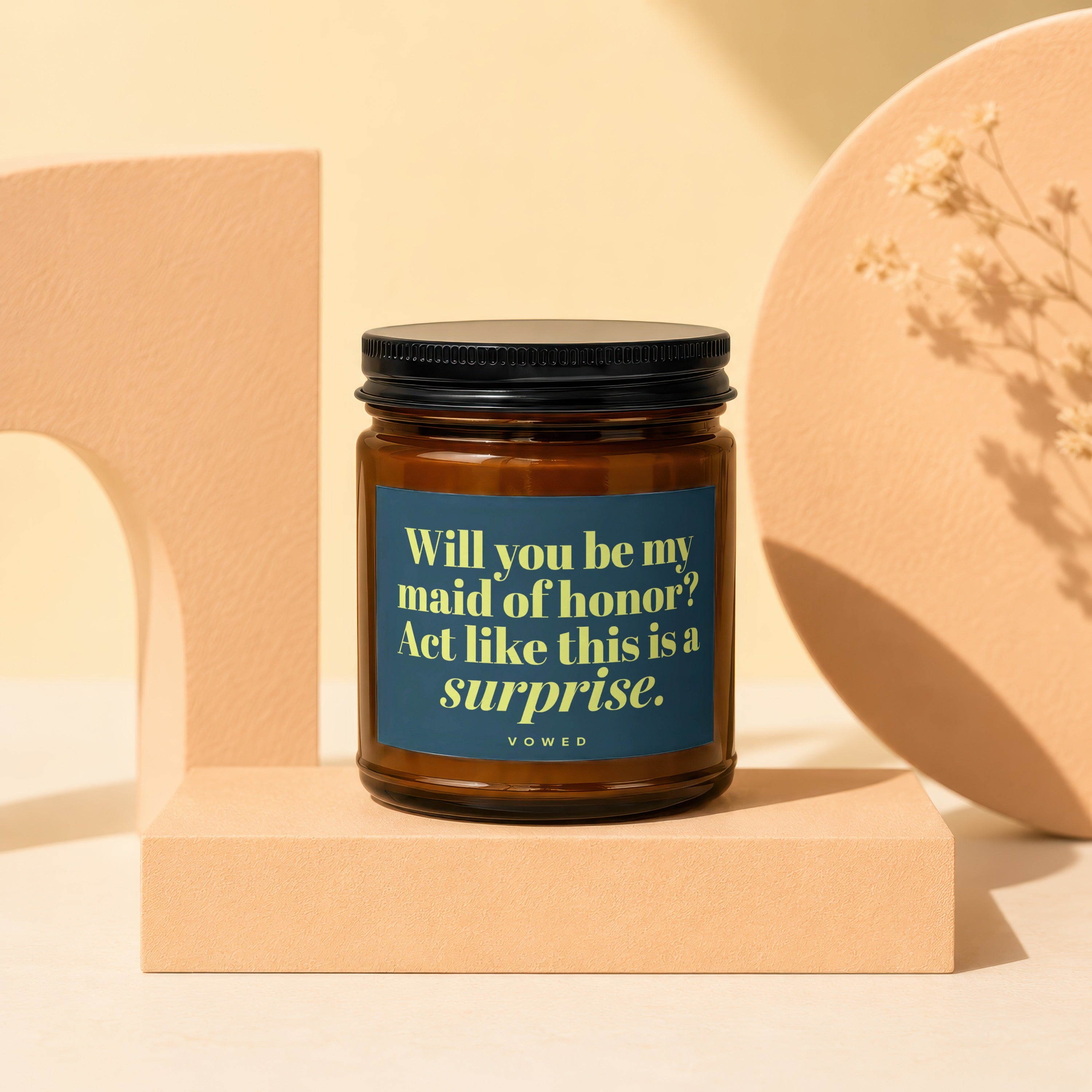 Brown candle with blue label asking, "Will you be my maid of honor? Act like this is a surprise."