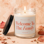 Lit glass candle with black lid, reads "Smells Like Welcome To The Family"