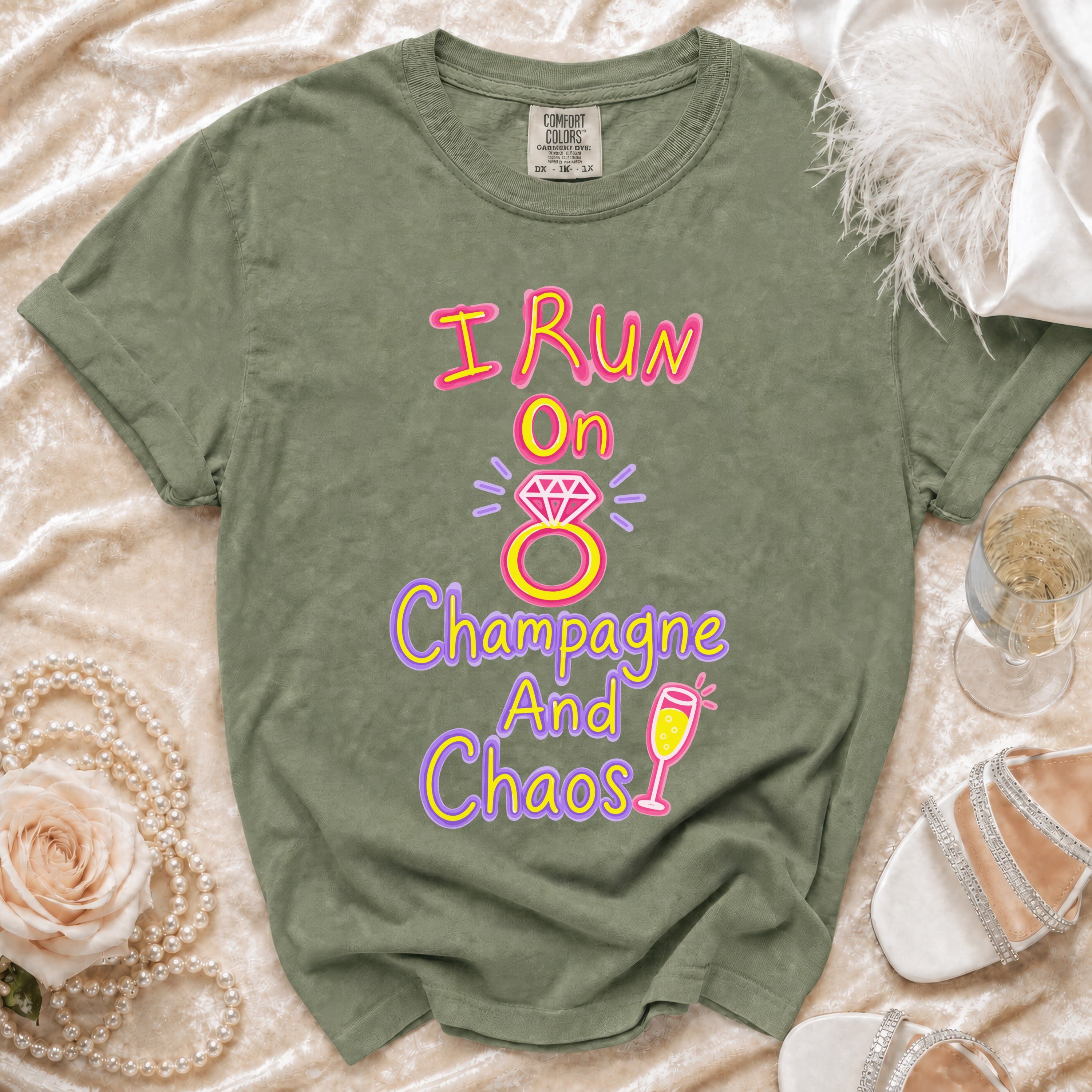Olive green t-shirt with "I Run On Champagne And Chaos" text and graphics.