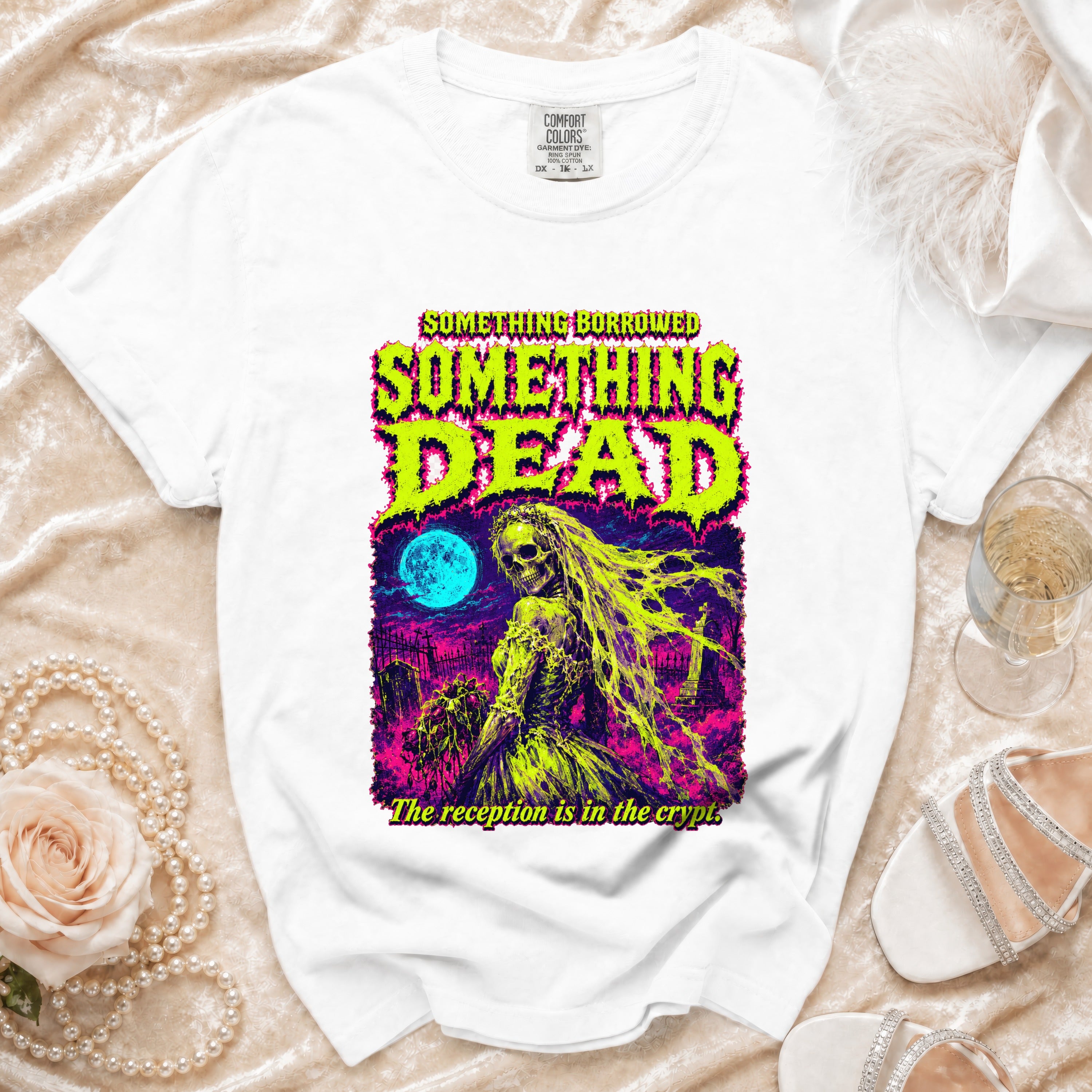 White t-shirt with graphic art of a skeletal bride in a graveyard, with text "SOMETHING BORROWED SOMETHING DEAD".