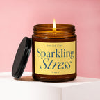 Burning amber jar candle with yellow label reading "Smells Like Sparkling Stress."