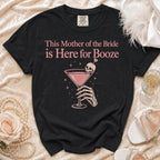 Black t-shirt with "This Mother of the Bride is Here for Booze" text and skeleton hand holding cocktail.