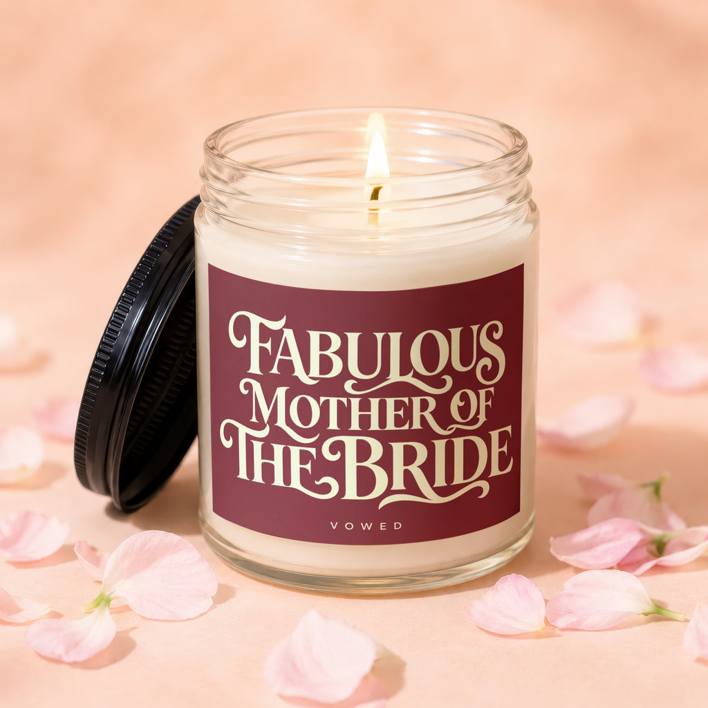 Candle with "Fabulous Mother of the Bride" text, lit wick, and scattered petals.