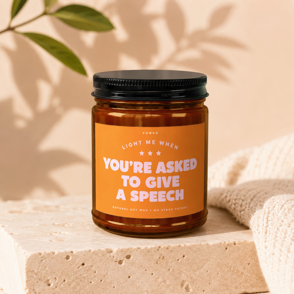 Amber jar candle with orange label reading "Light me when you're asked to give a speech."