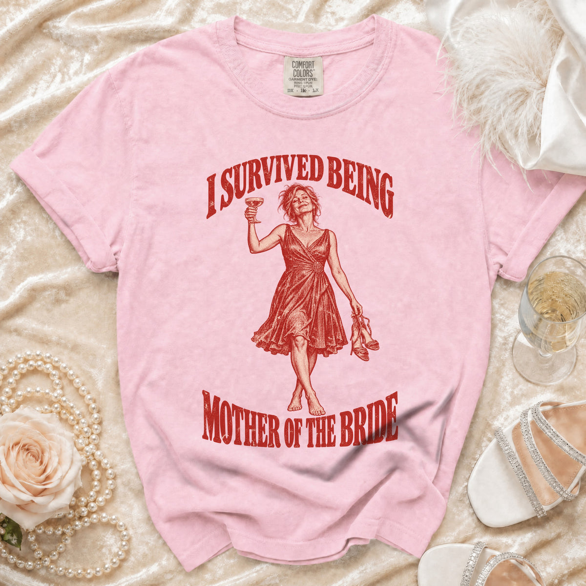 Pink t-shirt with red graphic of woman holding wine and text "I SURVIVED BEING MOTHER OF THE BRIDE".