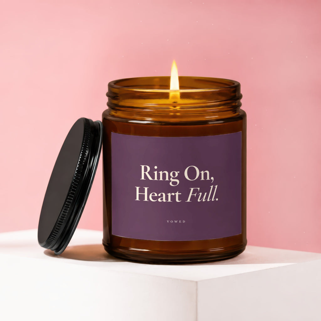 Amber jar candle with lit flame and black lid, text reads "Ring On, Heart Full."