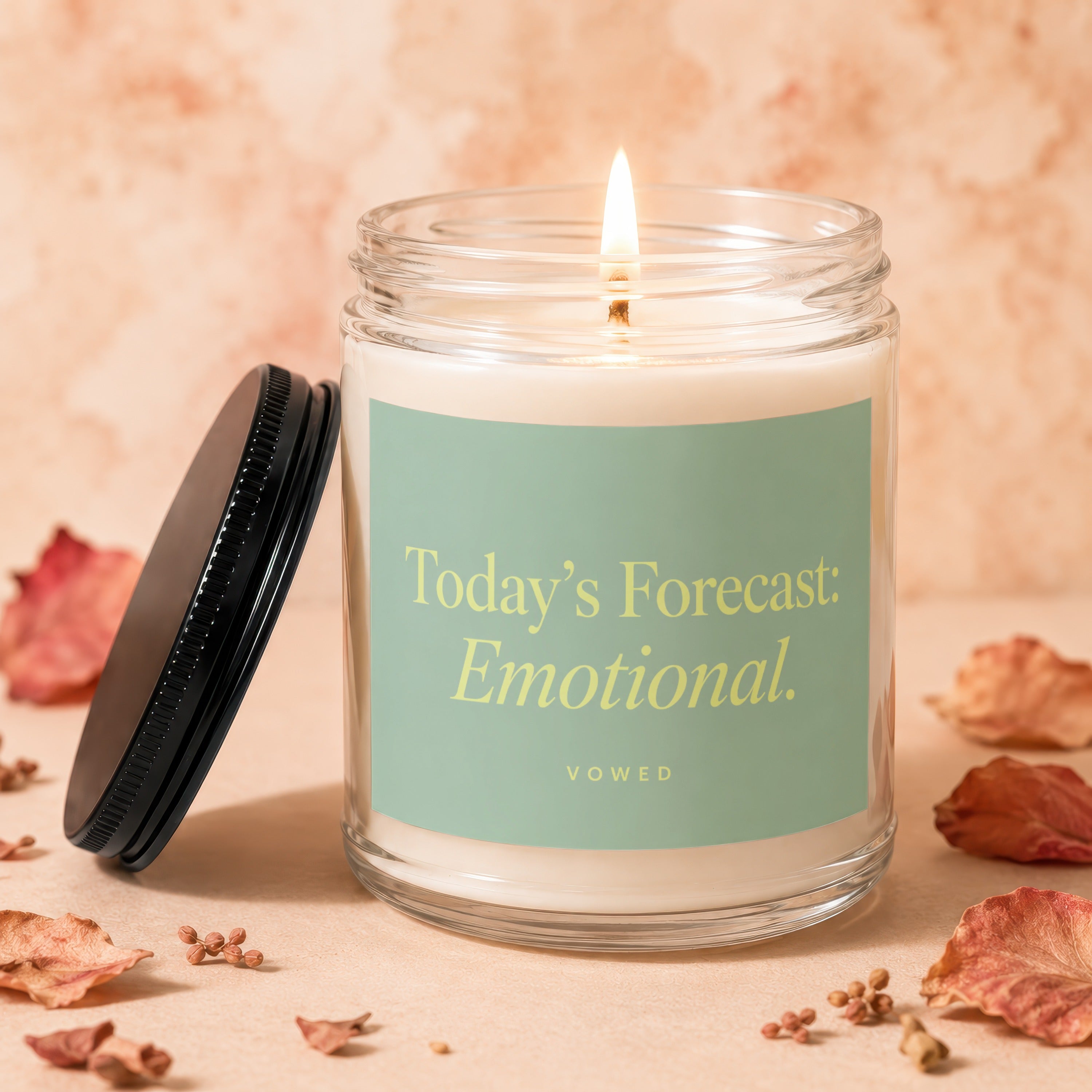 Scented candle with lit wick, "Today's Forecast: Emotional" text on label.
