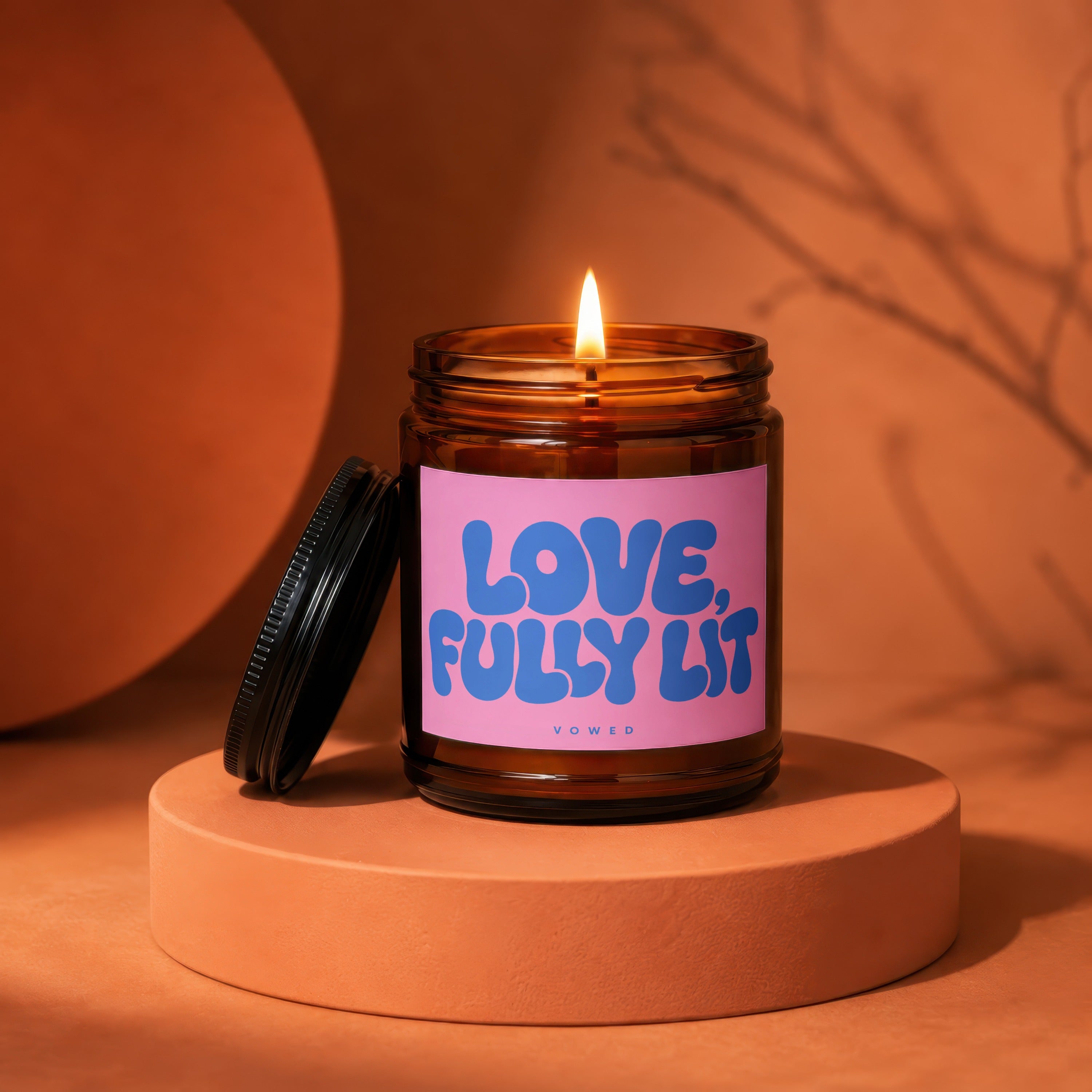 Amber jar candle with pink label that reads "LOVE, FULLY LIT, VOWED".