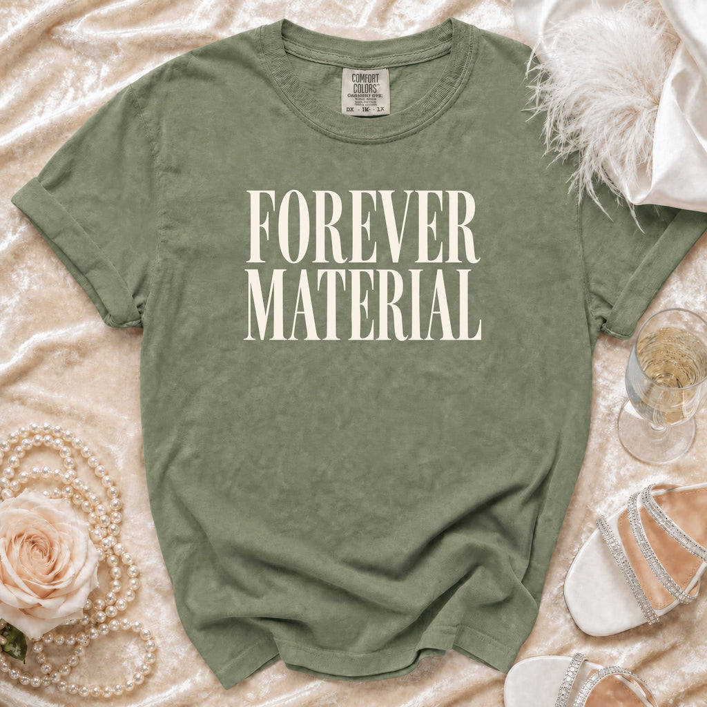 Olive green t-shirt with "FOREVER MATERIAL" text, styled with pearls and shoes.