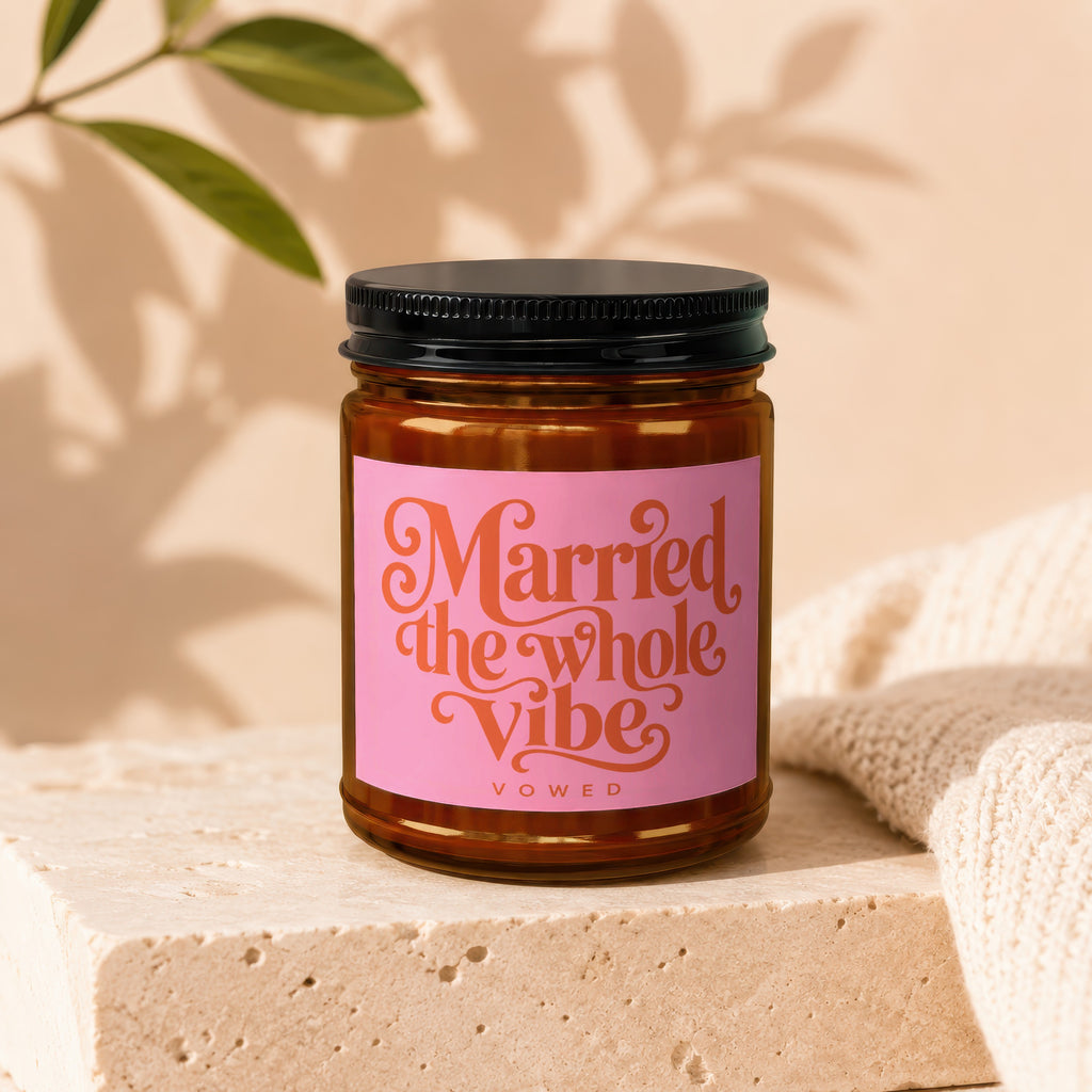 Amber candle in a jar with pink label that reads "Married the whole vibe VOWED".