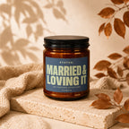 Candle with dark lid and label reading "STATUS: MARRIED & LOVING IT".