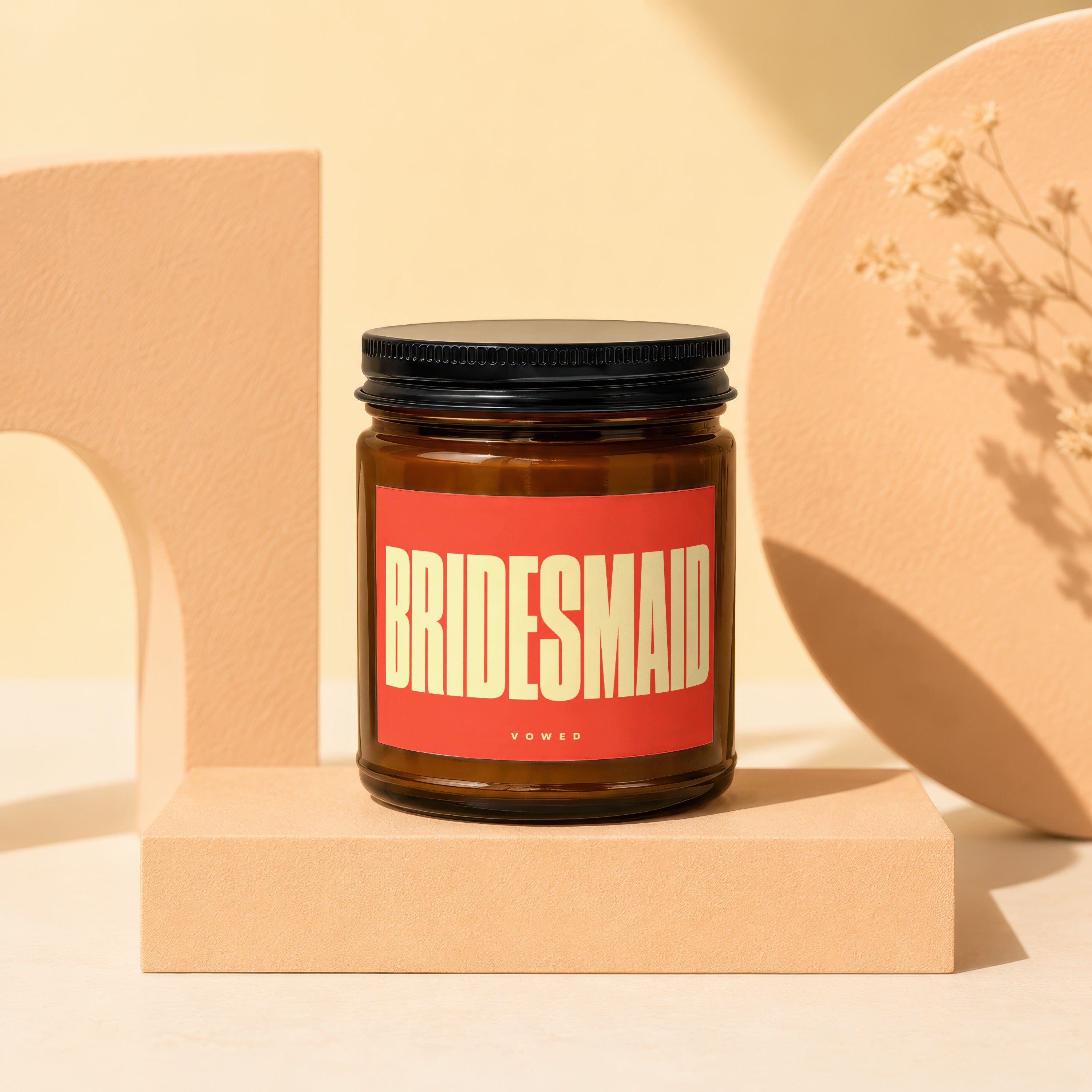 Amber jar candle with "BRIDESMAID" and "VOWED" text on a red label.