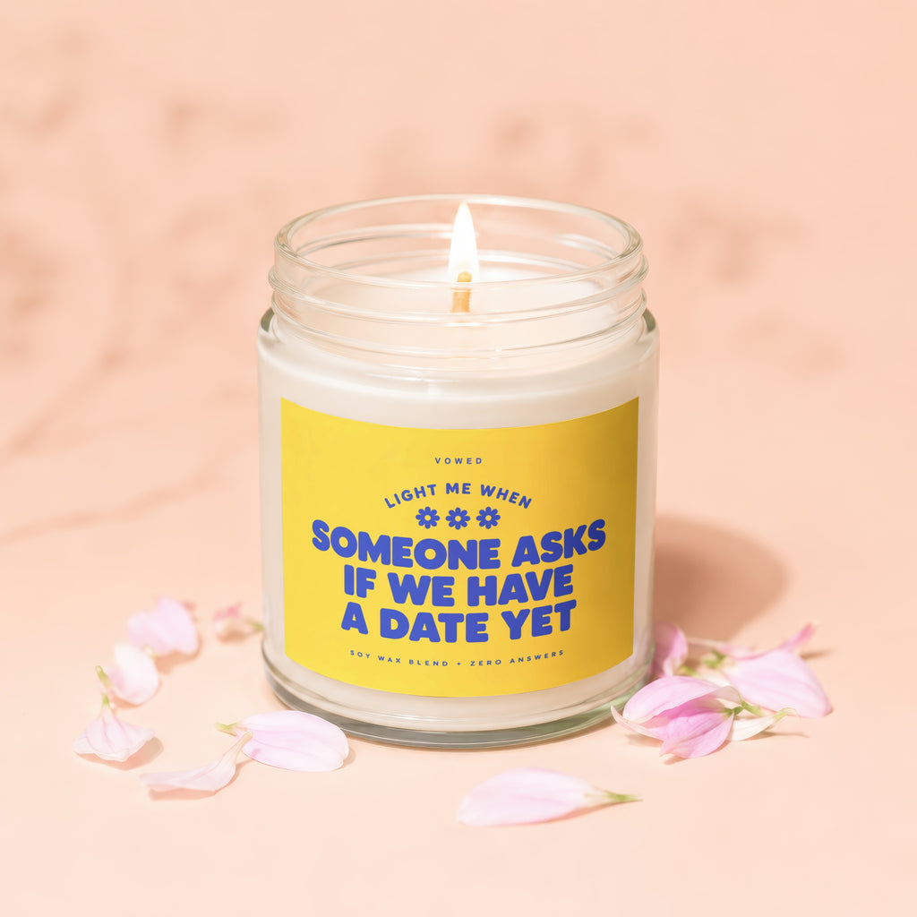 Soy wax candle with yellow label: "Light me when someone asks if we have a date yet."