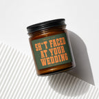 Amber candle in glass jar with black lid, green label reads "Smells like Sh*t Faced At Your Wedding"