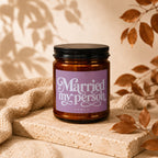 Brown glass candle with purple label reading "Married my person" and "vowed".