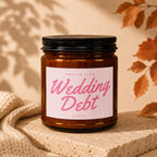 Amber candle with black lid labeled "Smells Like Wedding Debt Vowed".