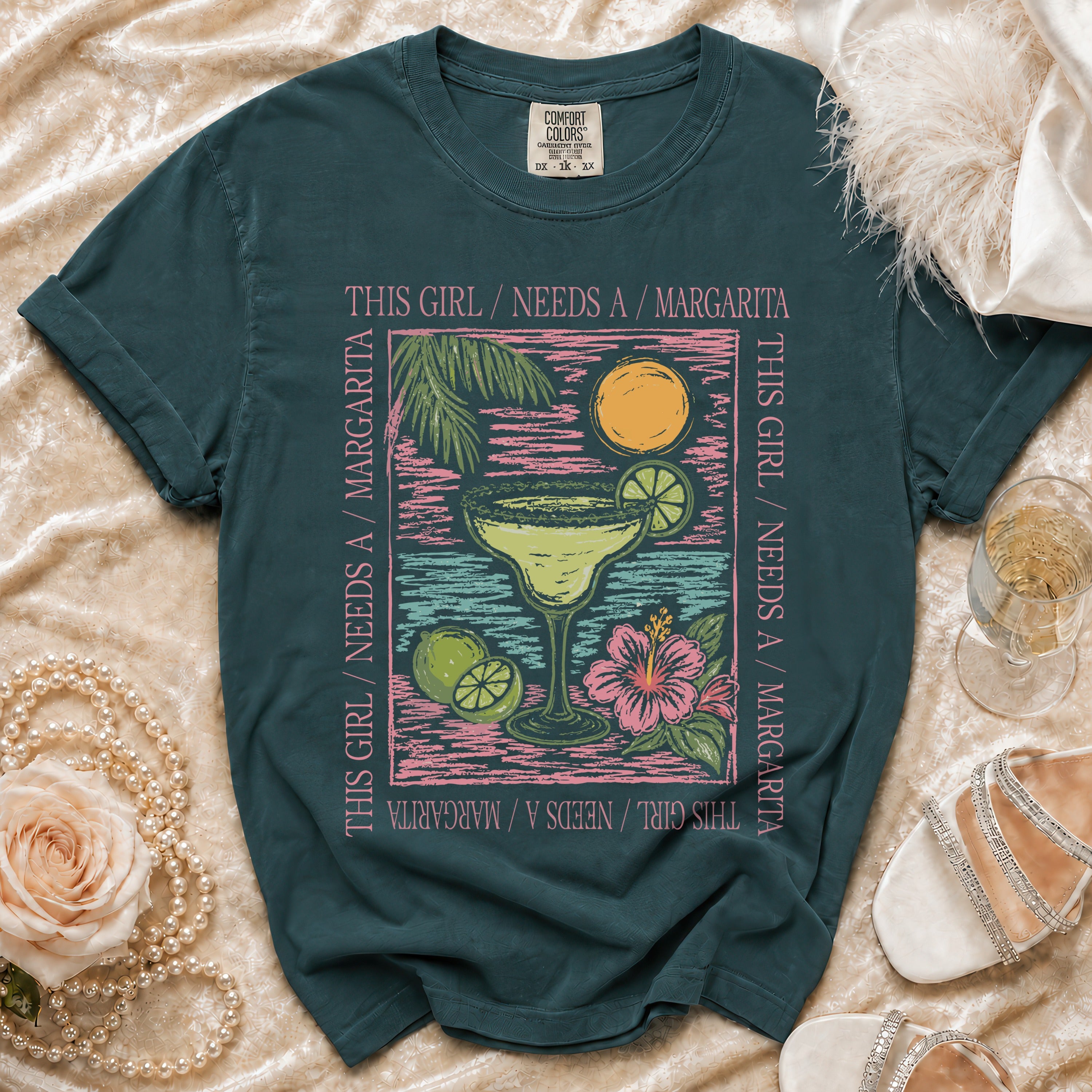 Teal t-shirt with a margarita graphic and the text "This girl needs a margarita."