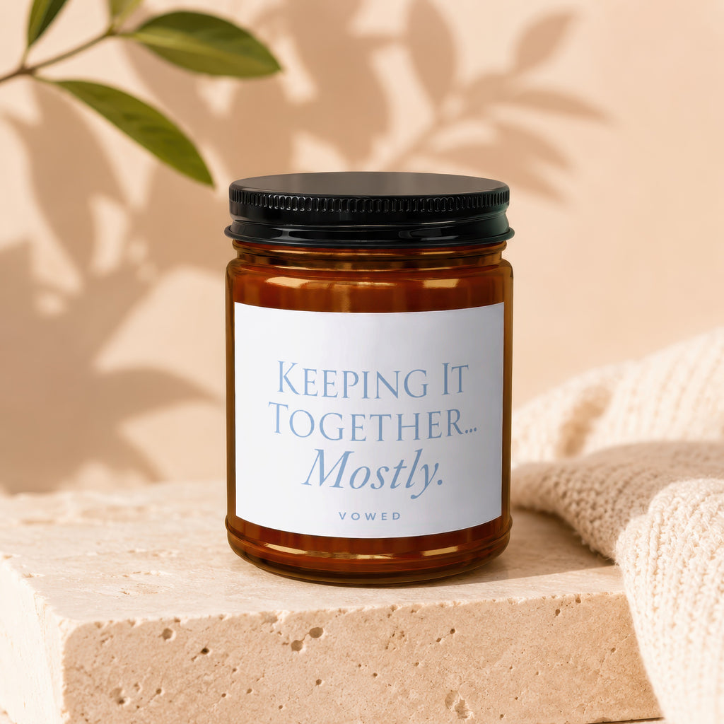 Amber candle with "Keeping it Together.. Mostly." text on a white label, Vowed below.