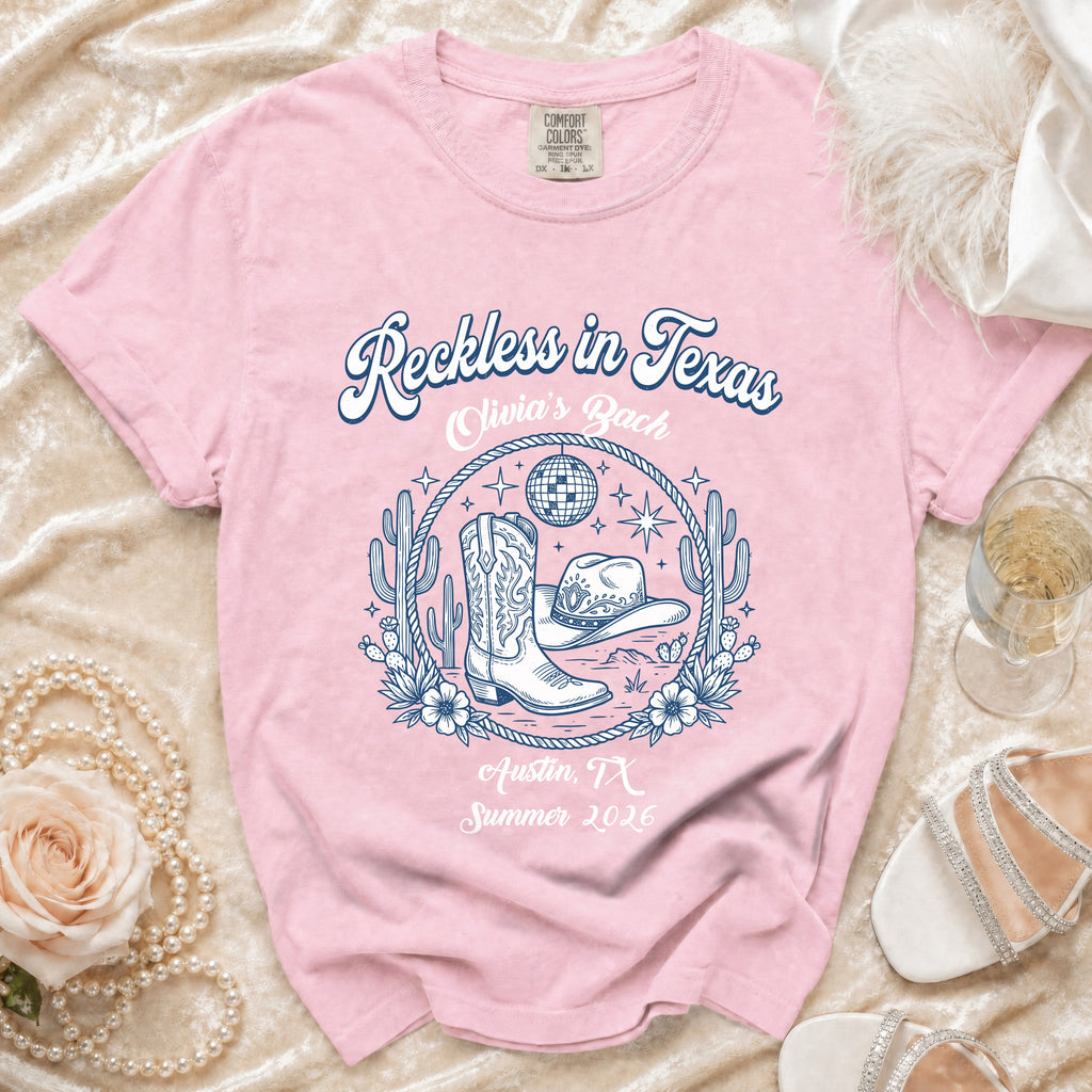 Pink t-shirt with "Reckless in Texas" and western graphics, Austin TX Summer 2026.