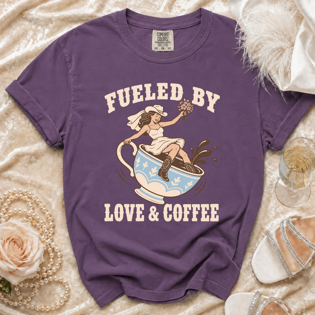 Purple t-shirt with bride sitting in coffee cup graphic and text "Fueled by Love & Coffee".