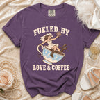 Purple t-shirt with bride sitting in coffee cup graphic and text "Fueled by Love & Coffee".