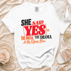 White t-shirt with "She Said Yes to the Dress, The Drama & the Open Bar" graphic.