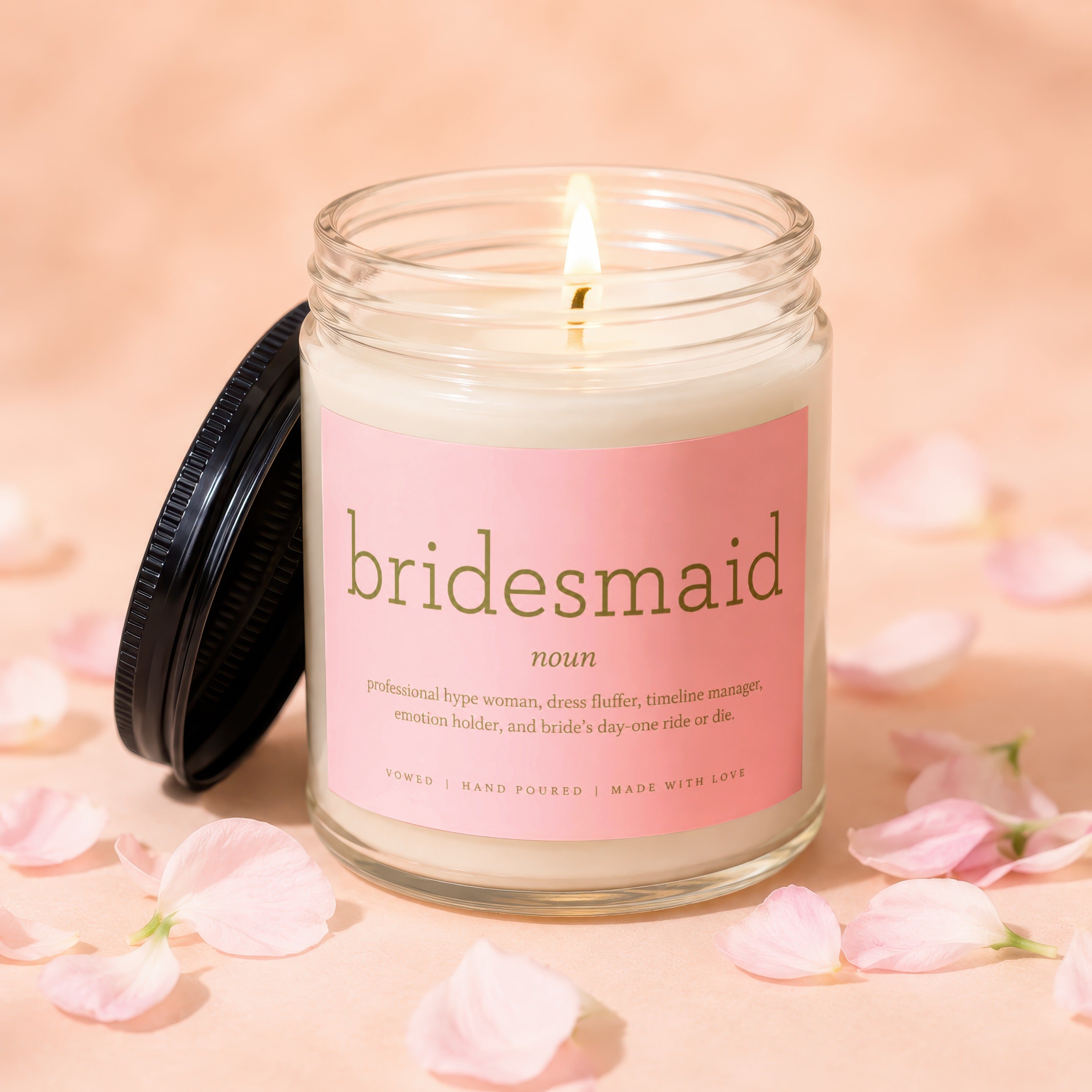 Bridesmaid candle with definition on label, lit flame, and pink petals.