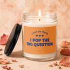 Candle with orange label reading "LIGHT ME WHEN I POP THE BIG QUESTION"