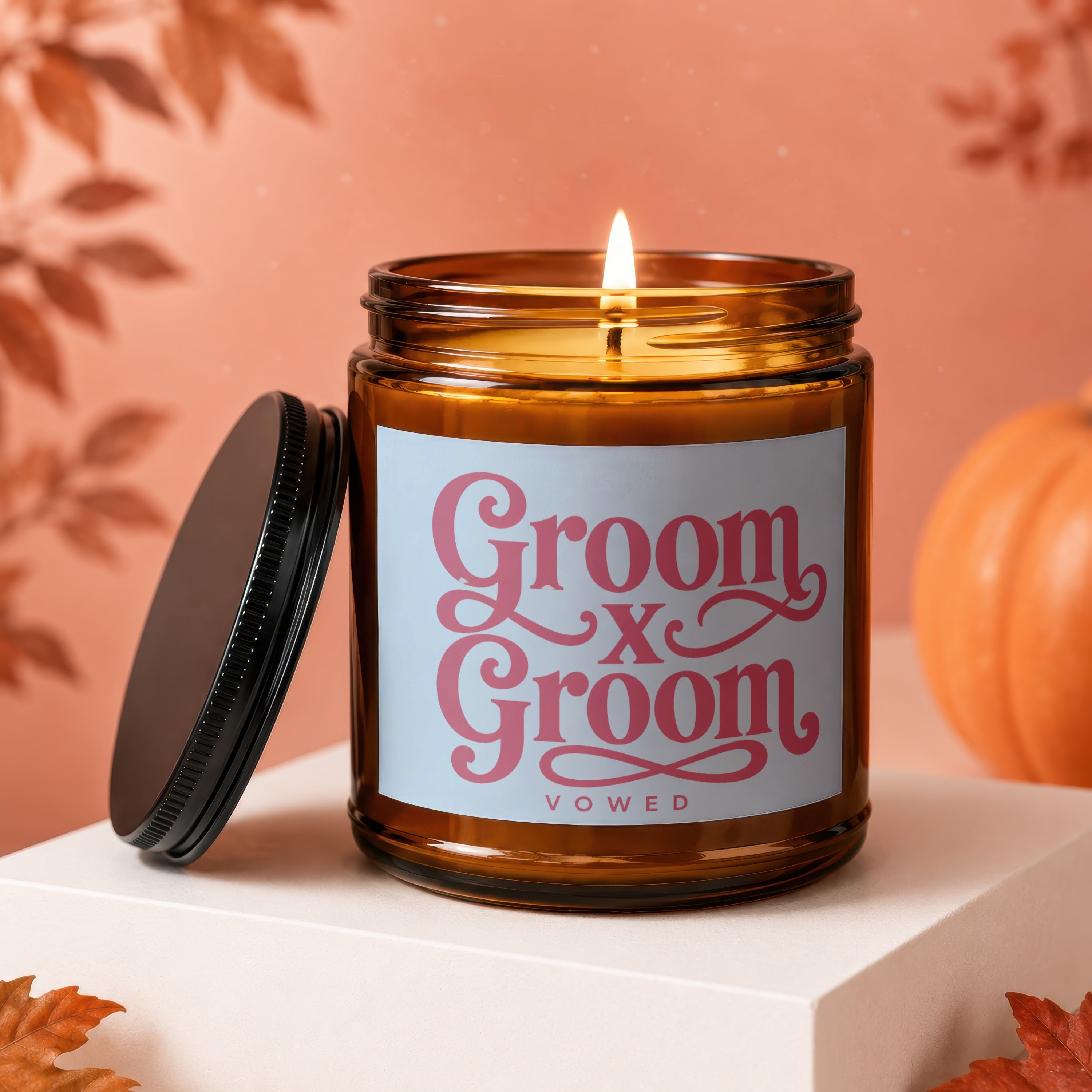Amber candle with lit wick, "Groom x Groom Vowed" text, lid, and pumpkin.