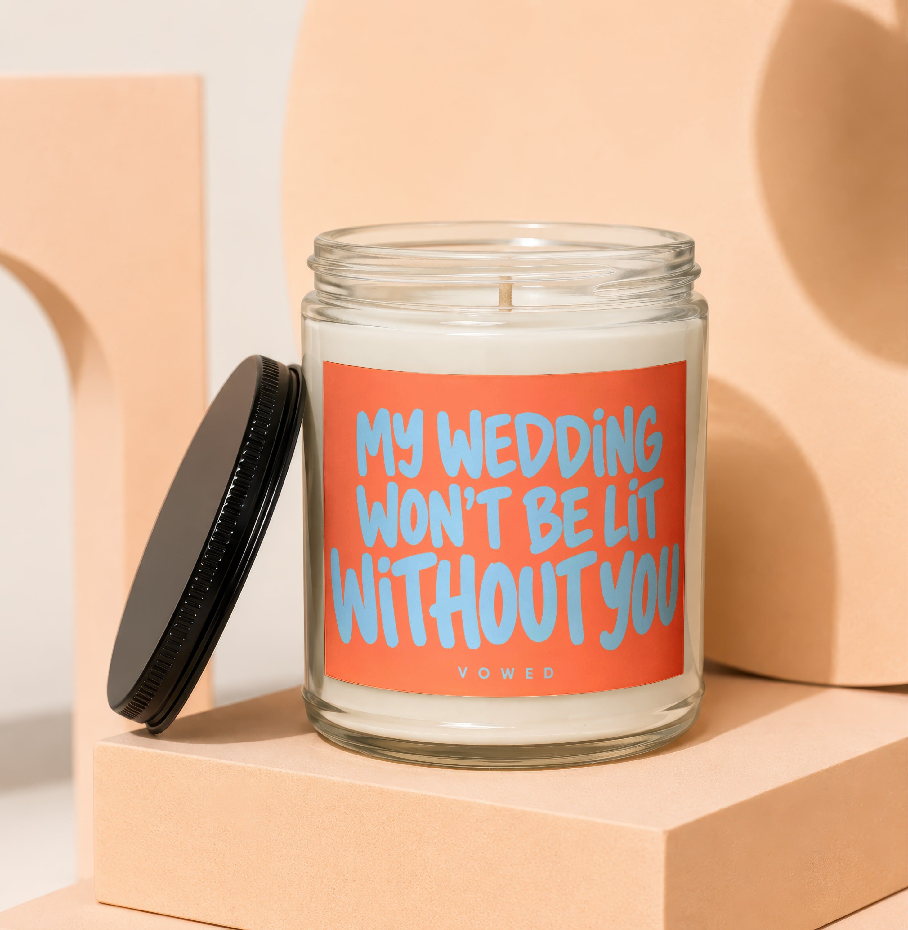 Glass candle with orange label reading "MY WEDDING WON'T BE LIT WITHOUT YOU".