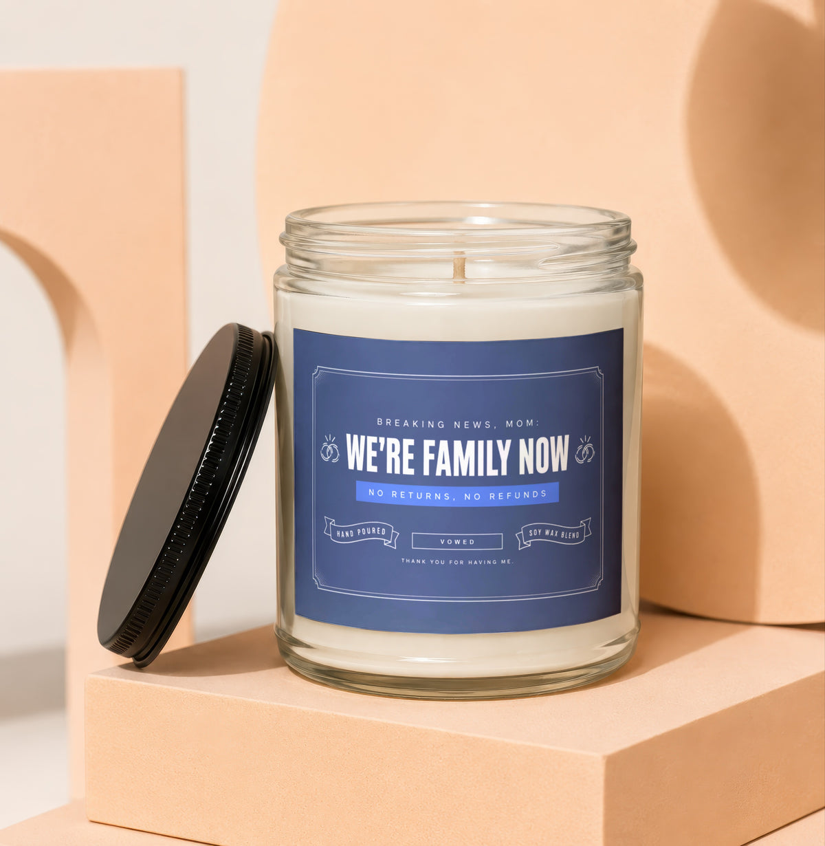 Glass candle with blue label reading "We're Family Now, Mom".