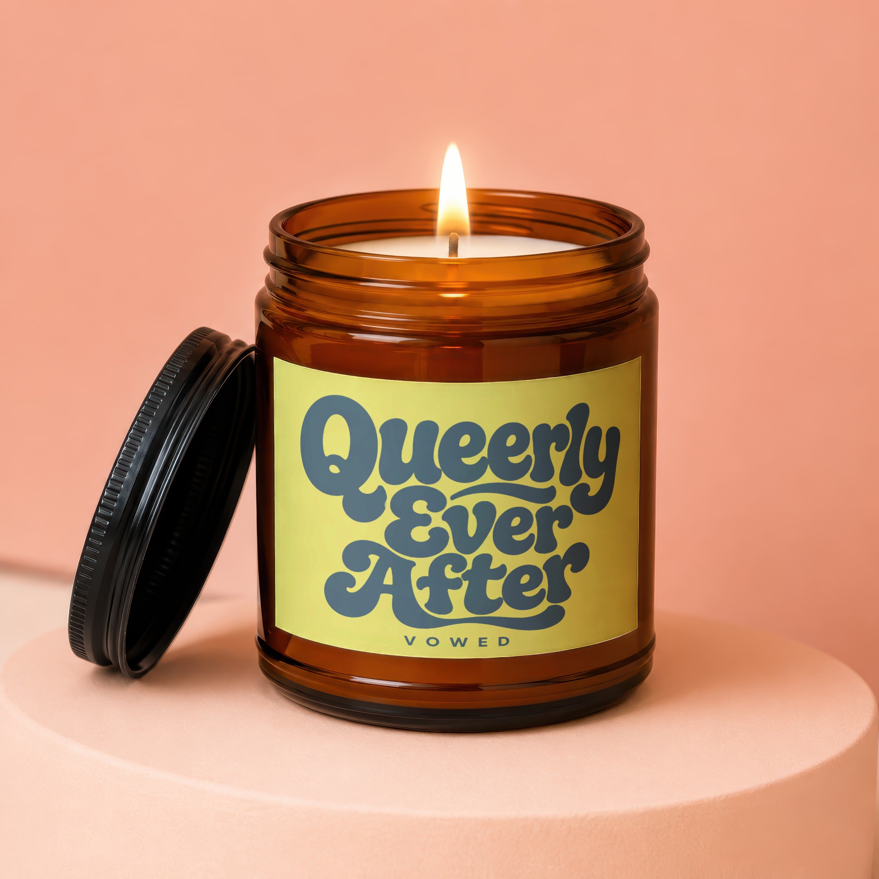 Amber candle with a lit wick and lid removed, featuring a yellow label with blue text.