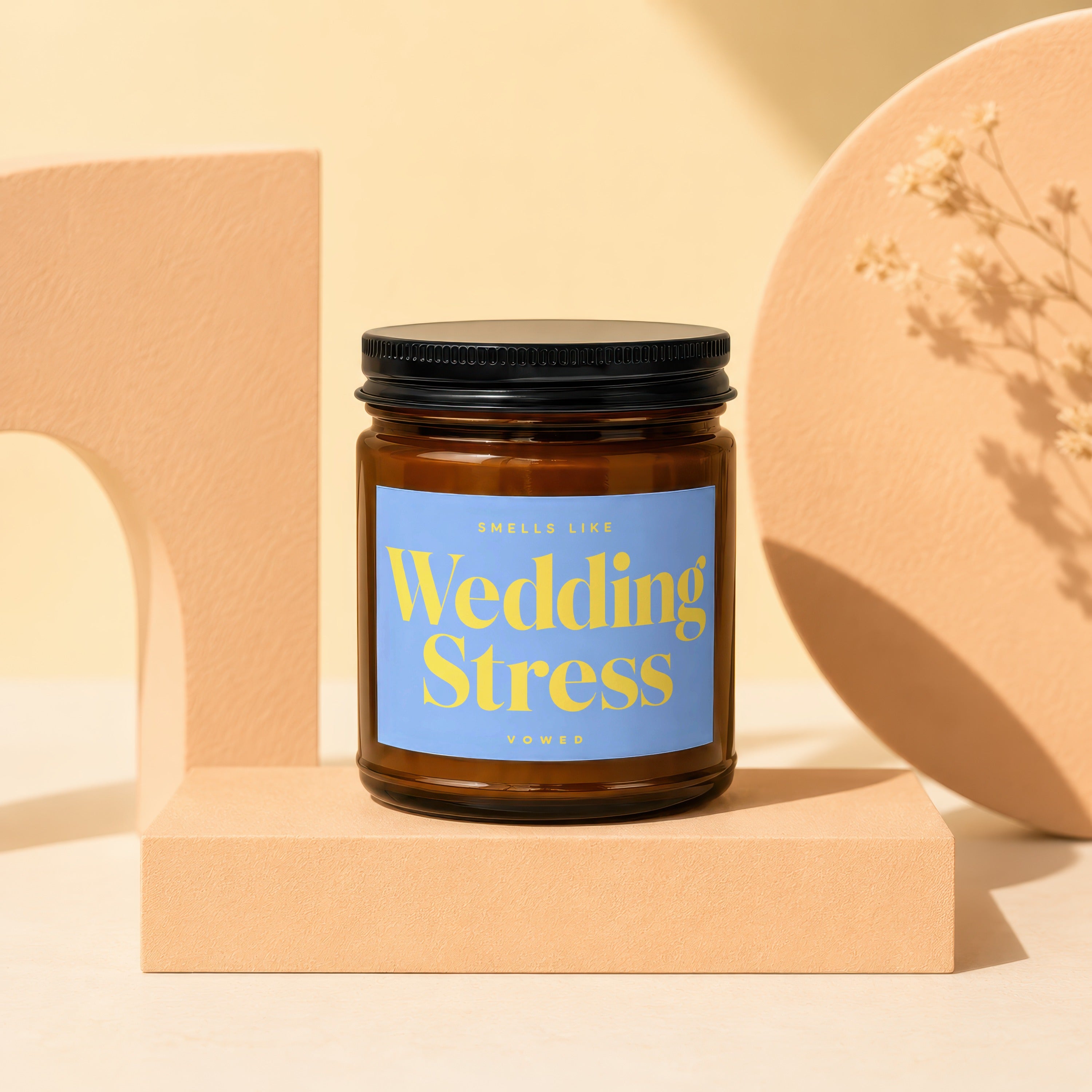 Brown glass candle labeled "Wedding Stress" by Vowed, on a beige pedestal.