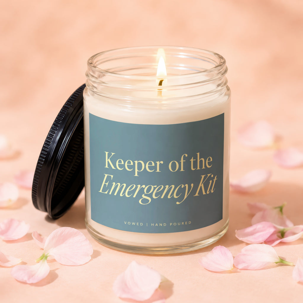 Keeper of the Emergency Kit candle, hand-poured, with a lit flame and black lid.