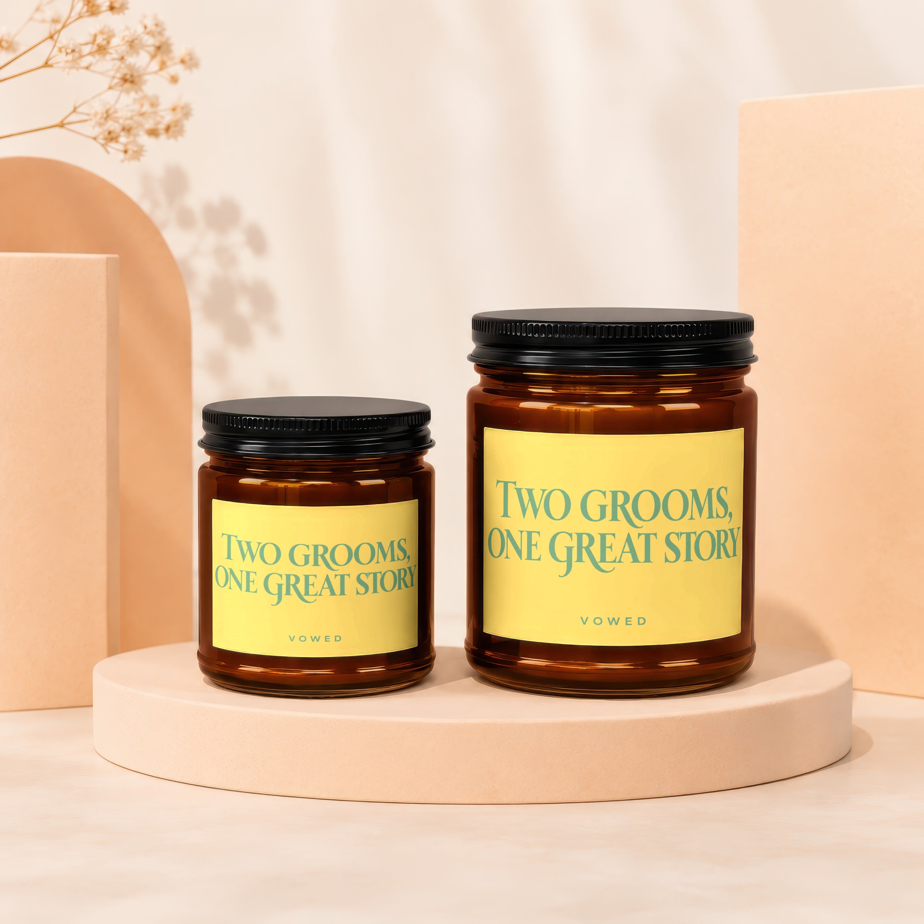 Two amber glass candles, one large, one small, with yellow labels stating "Two Grooms, One Great Story".