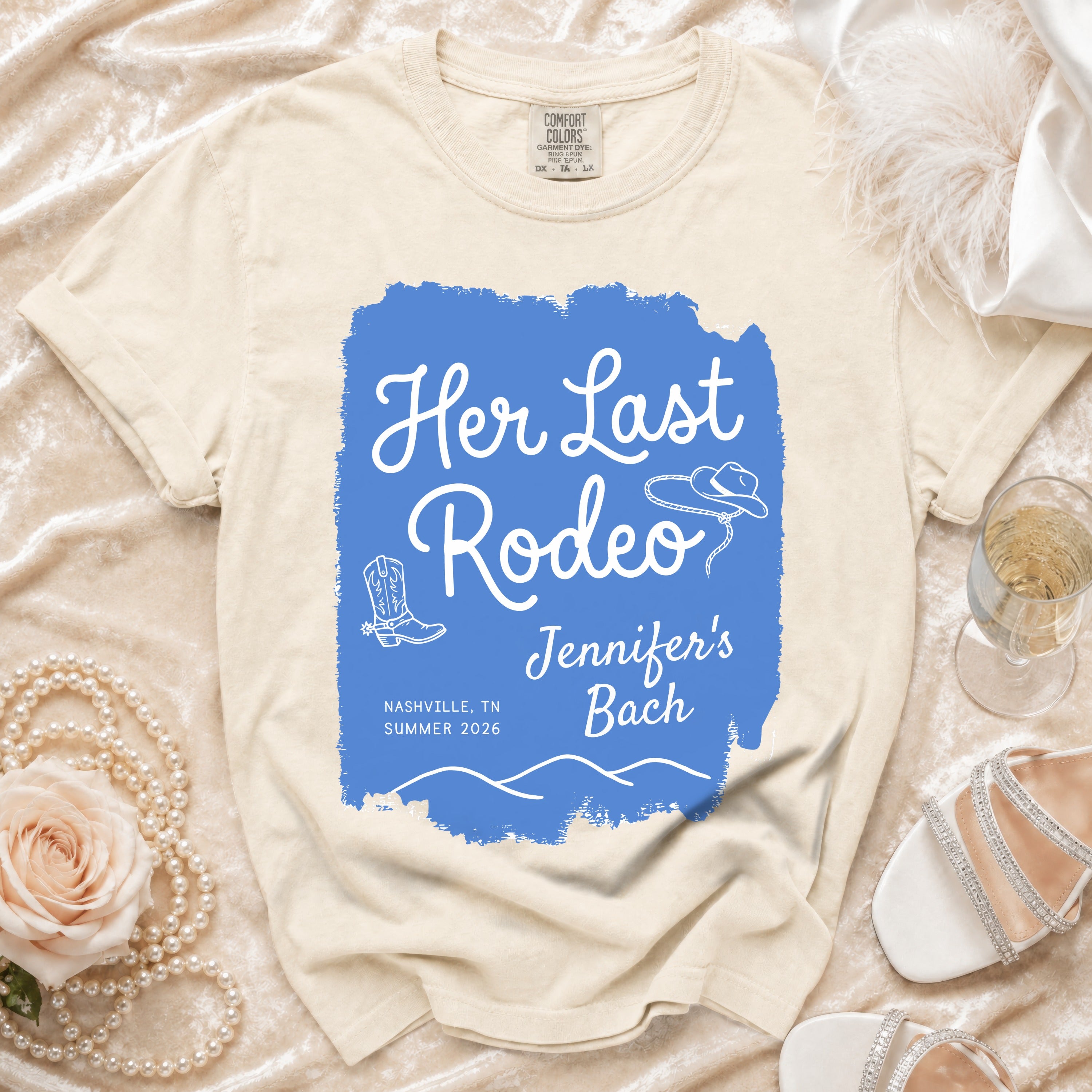 Cream t-shirt with "Her Last Rodeo" text, cowboy hat, and boots.