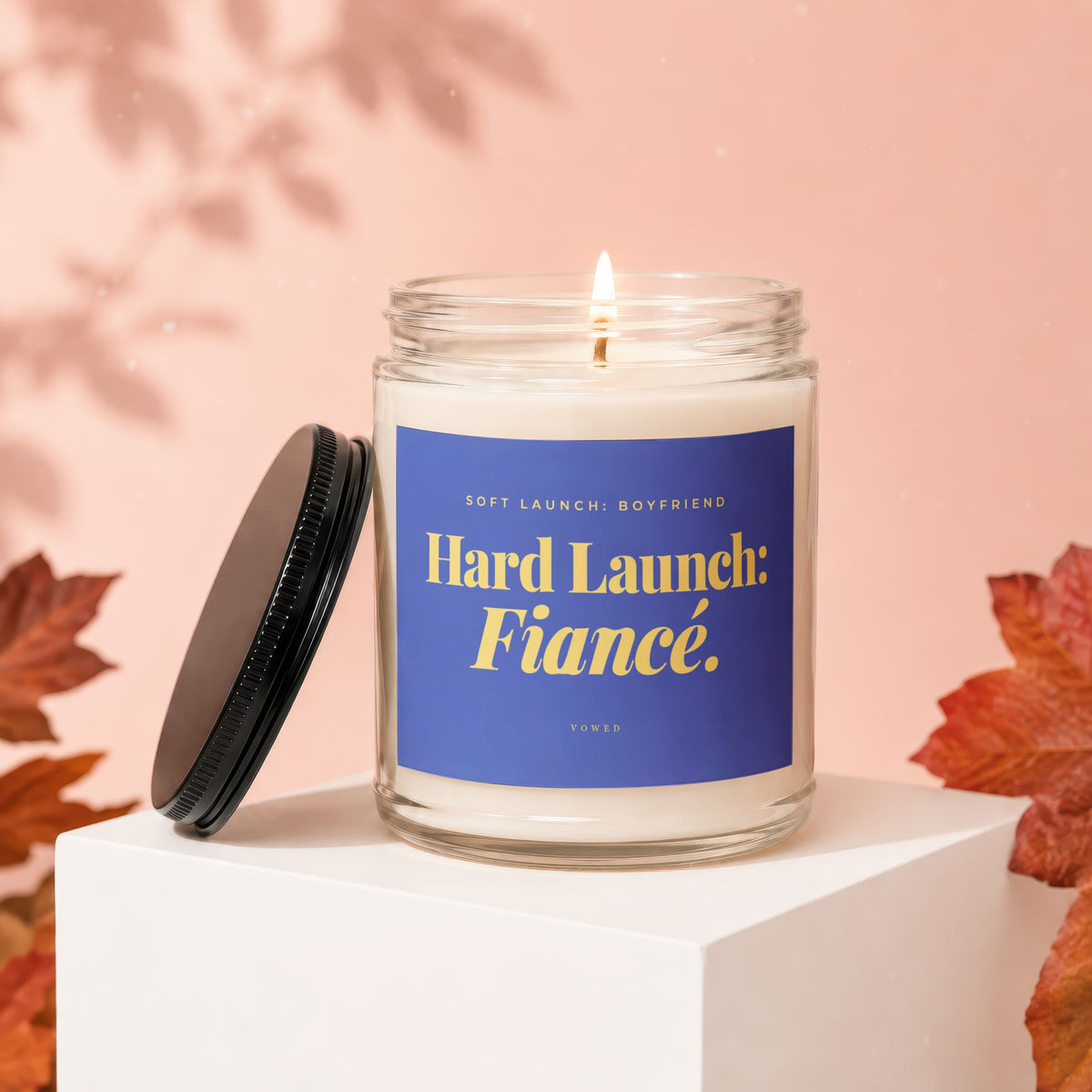 Candle with blue label reading "Hard Launch: Fiancé." in gold text.