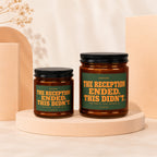 Two amber glass candles with black lids and green labels reading "STATUS: THE RECEPTION ENDED. THIS DIDN'T."