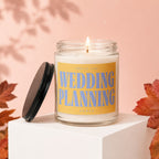 Candle with a lit wick and a yellow label reading "SMELLS LIKE WEDDING PLANNING VOWED".